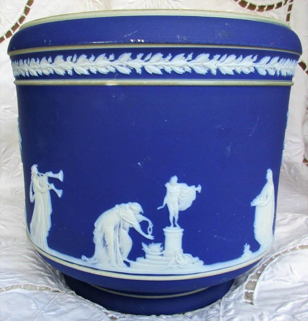 A deep cobalt blue Victorian jasperware ceramic jardiniere decorated with white classical relief figures, trees, and a foliate rim border. View IV