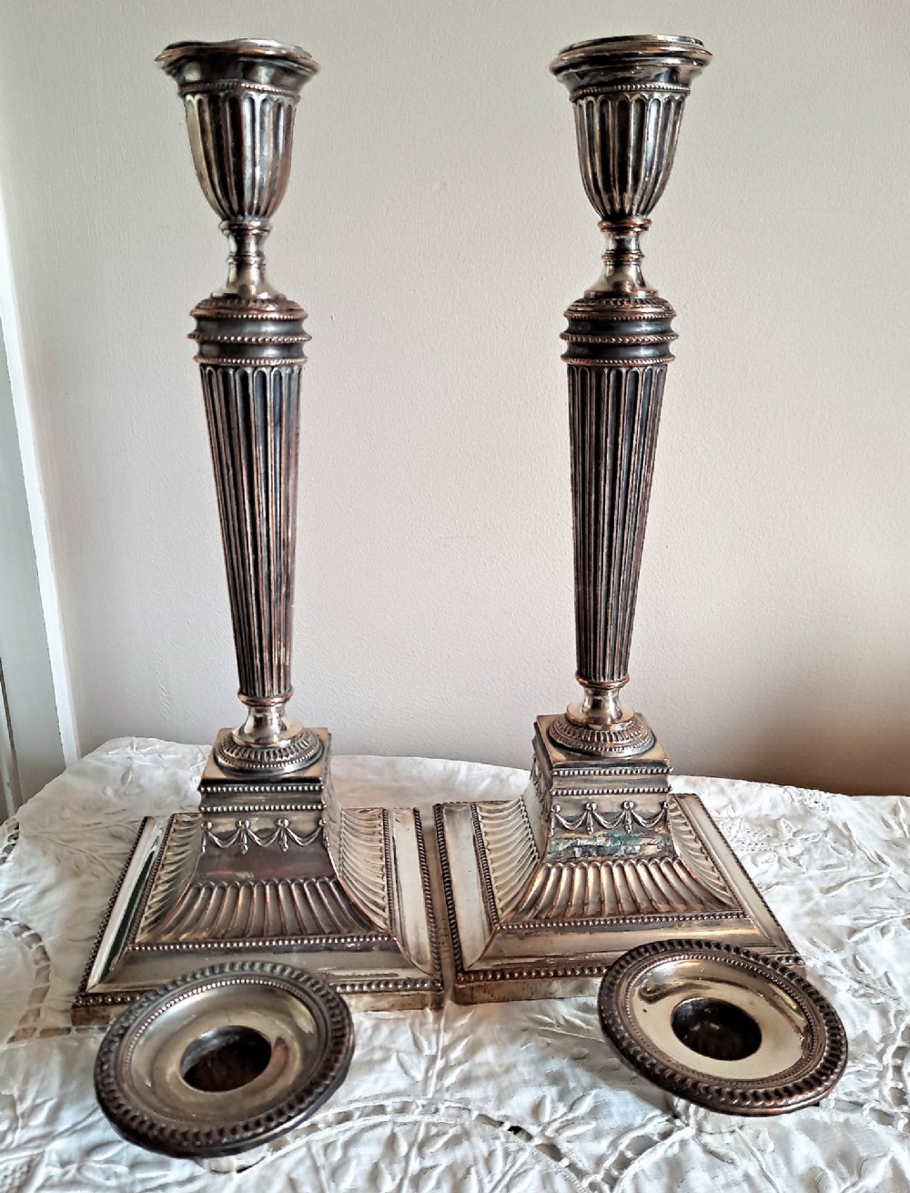 A pair of silver-plated Georgian candlesticks featuring fluted shafts, urn sconces, and square decorated bases showing copper wear. View III
