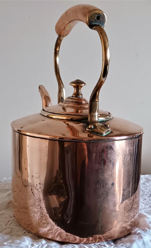 fig 1. A polished Victorian copper kettle featuring a gooseneck spout, fitted circular lid with finial, and fixed overhead handle.