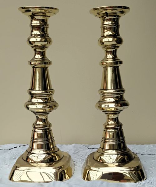 fig 1. A pair of polished gold-toned brass Victorian candlesticks featuring turned baluster stems and square bases.