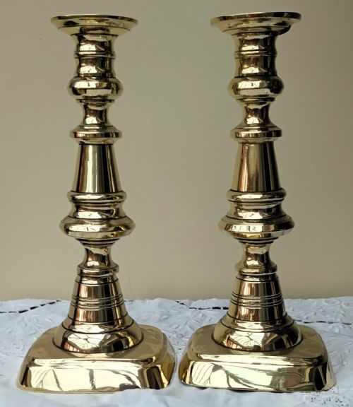 fig 2. A pair of polished gold-toned brass Victorian candlesticks featuring turned baluster stems and square bases.