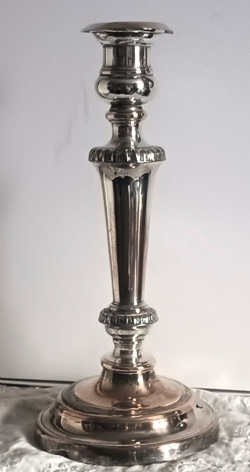 fig 1. A single silver-plated candlestick featuring a turned circular base, gadrooned collar detailing, and subtle copper showing through worn areas.