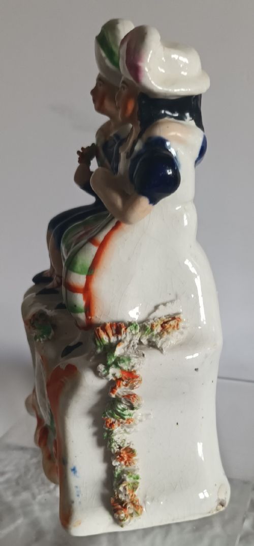 fig 1. A Victorian Staffordshire pottery figurine depicting two seated figures in Scottish dress set above a painted clock face.