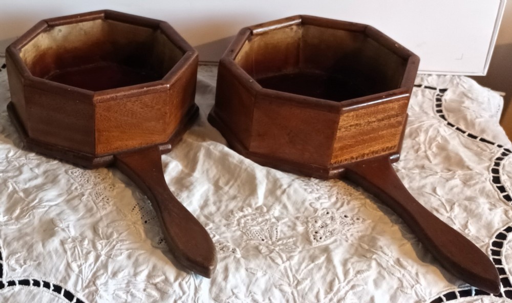 A pair of antique octagonal wooden alms dishes with extended carved handles, crafted in warm brown timber.