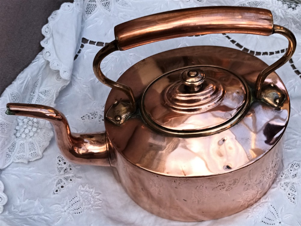 A polished Victorian copper kettle featuring a gooseneck spout, fitted circular lid with finial, and fixed overhead handle. View V