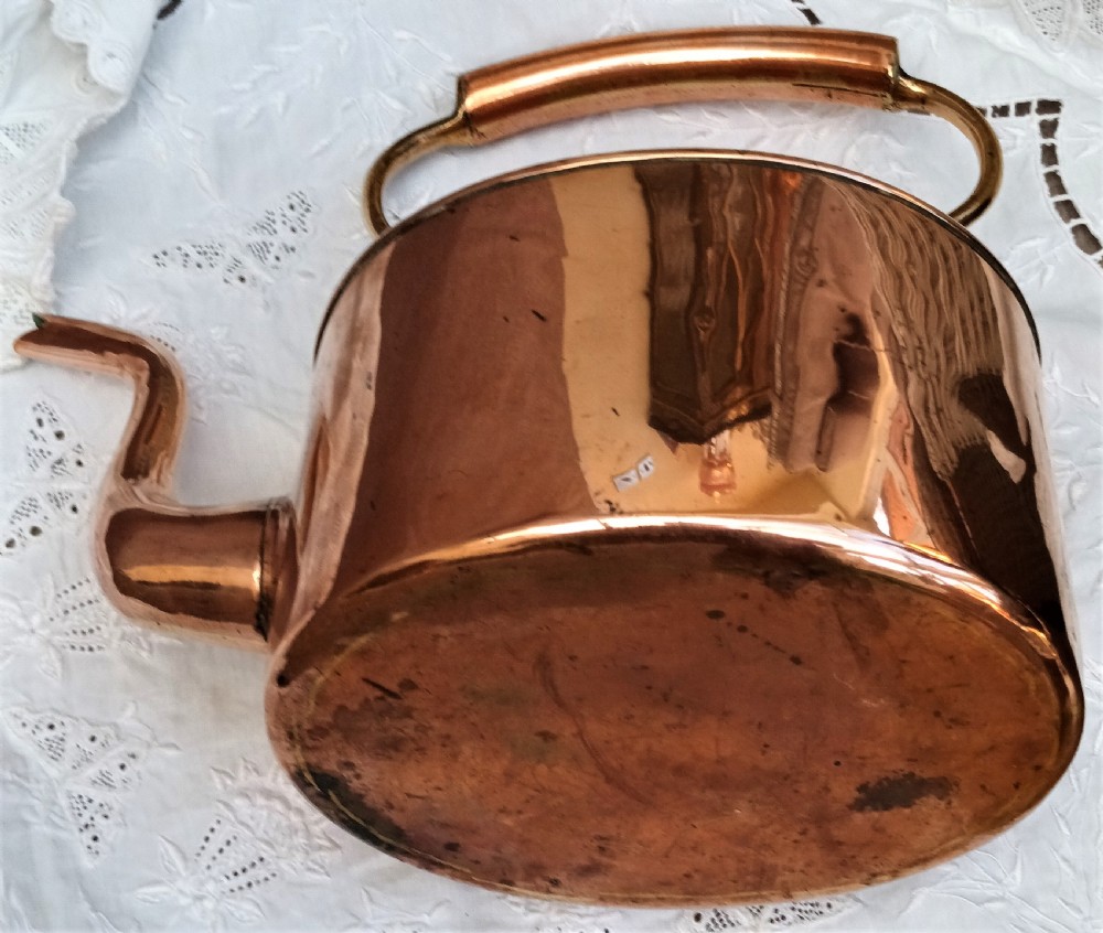A polished Victorian copper kettle featuring a gooseneck spout, fitted circular lid with finial, and fixed overhead handle. View VI