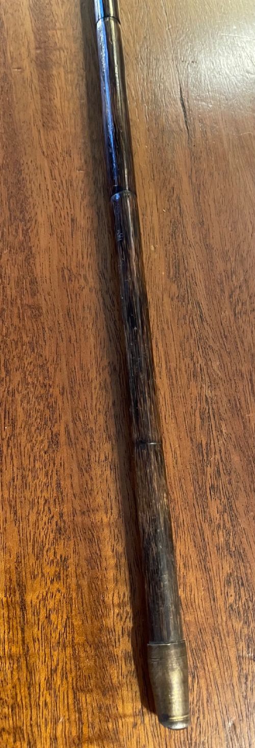 An antique walking stick with an embossed L-shaped silver handle featuring figurative motifs mounted on a dark brown bamboo shaft. View VI