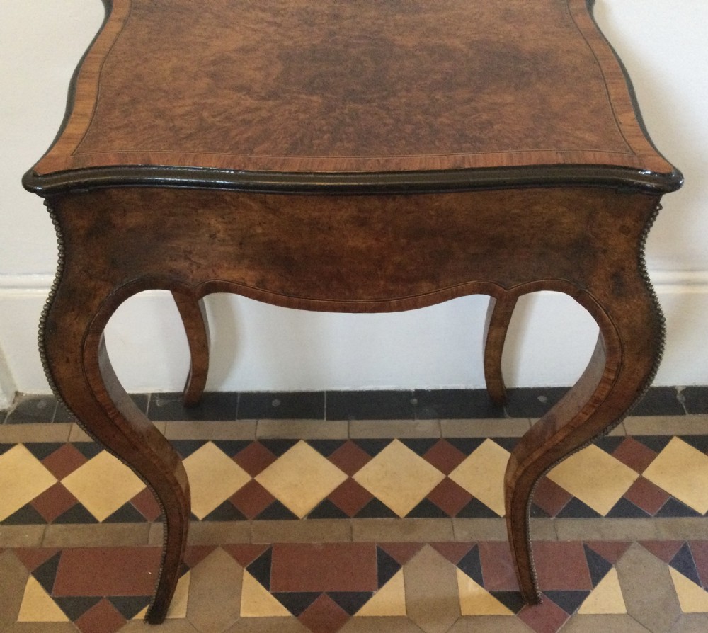 A late 19th-century burr walnut side table featuring serpentine edges, cabriole legs trimmed with brass studs, and a figured wood grain surface. View XVII