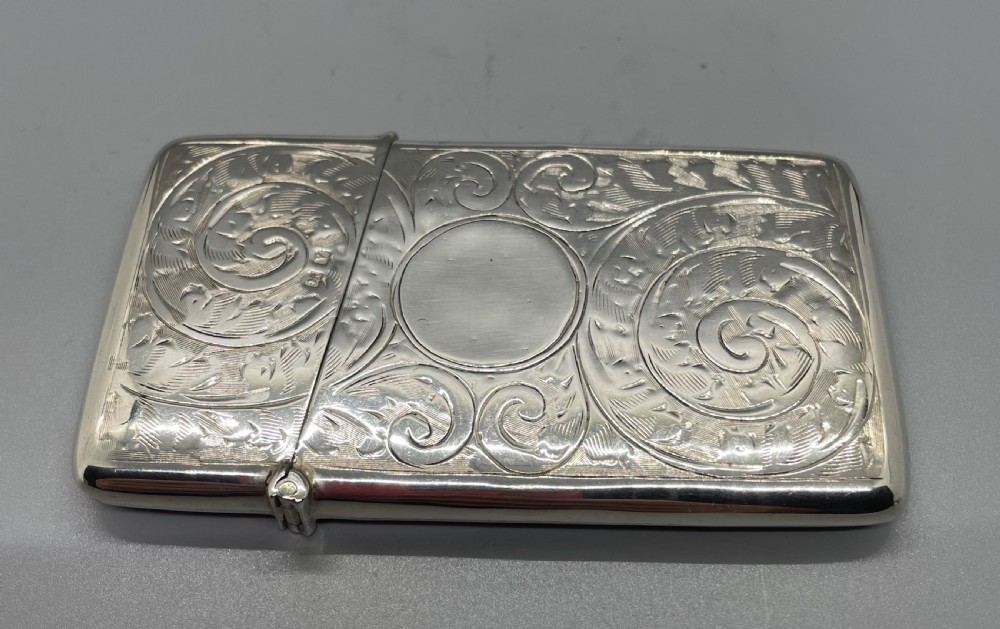 An engraved sterling silver card case featuring scrollwork patterns and a central circular cartouche. View V