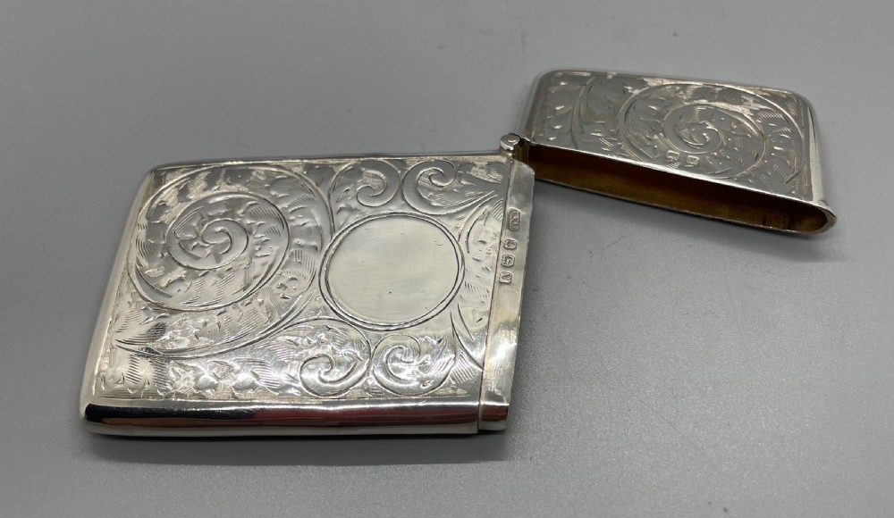 An engraved sterling silver card case featuring scrollwork patterns and a central circular cartouche. View VII