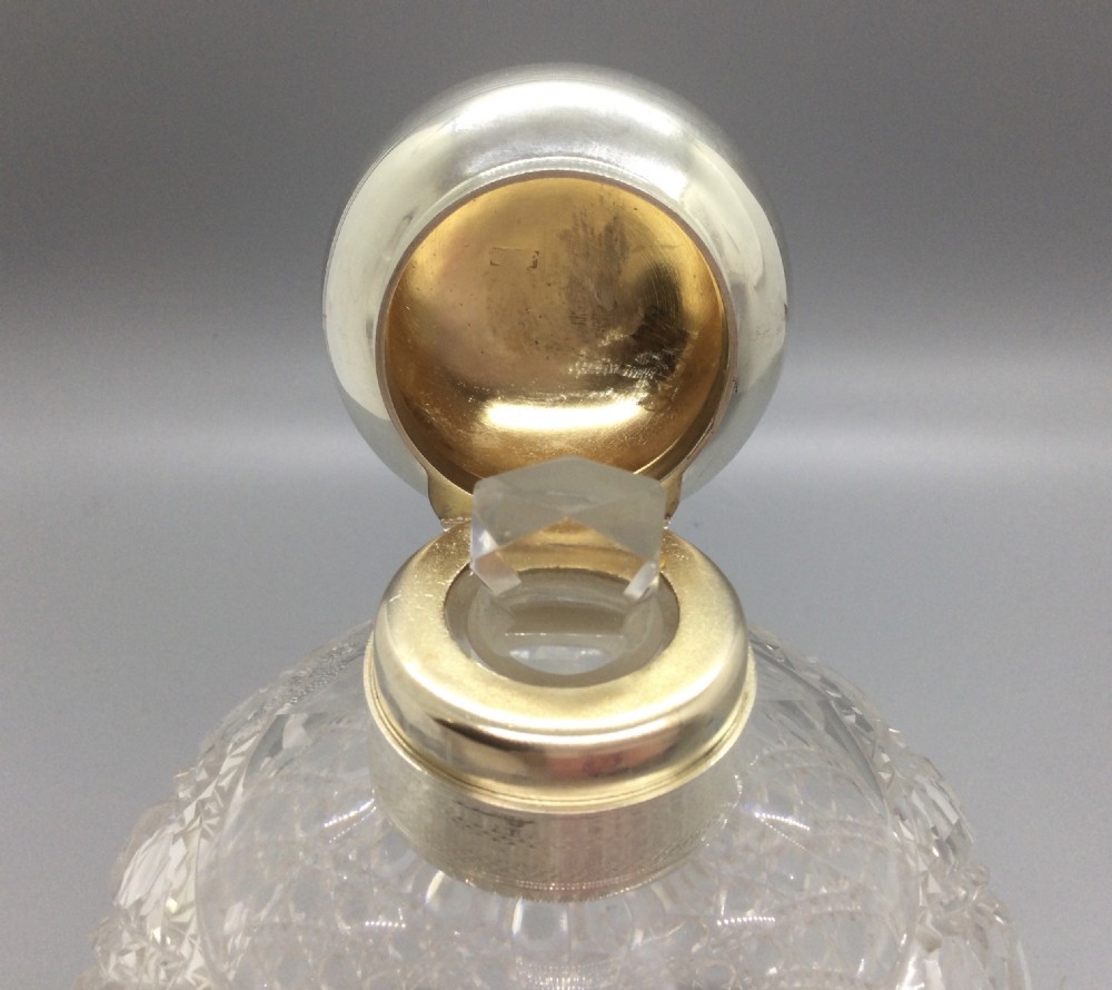 A round cut glass scent bottle with a polished globe-shaped sterling silver top. View VI
