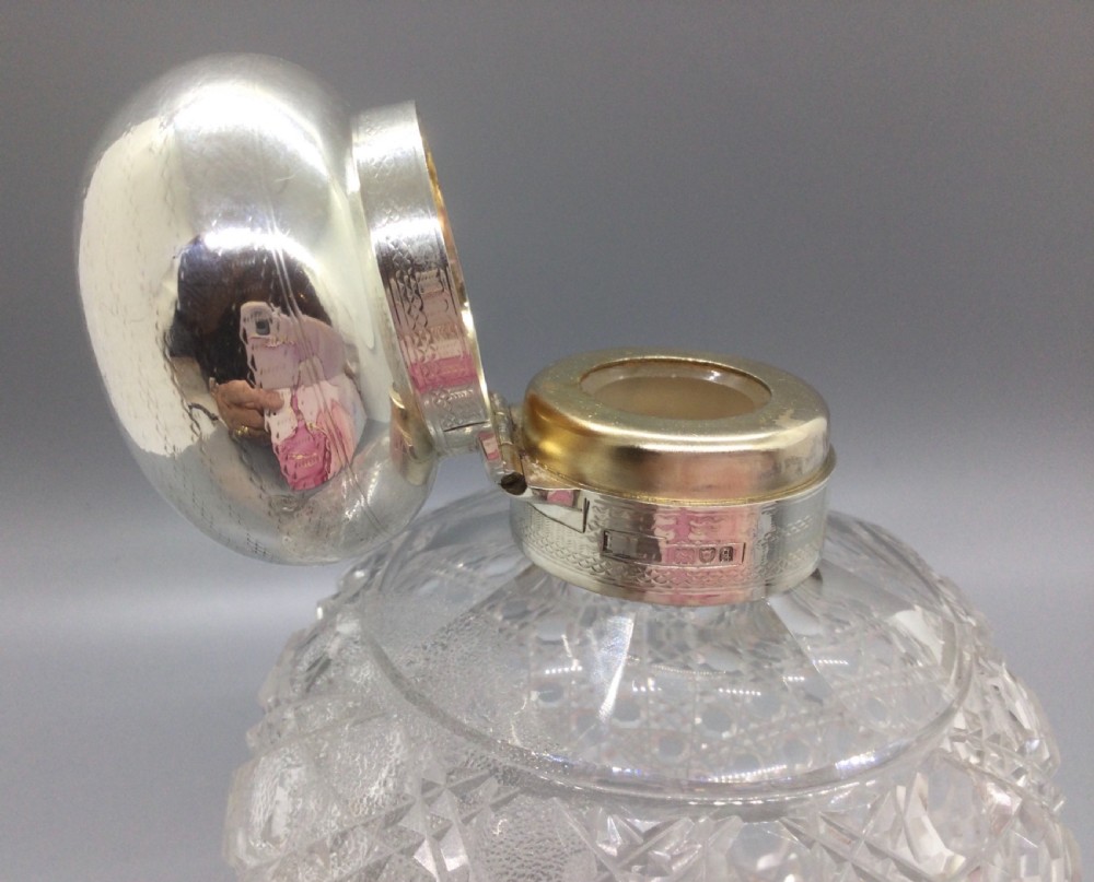 A round cut glass scent bottle with a polished globe-shaped sterling silver top. View IX