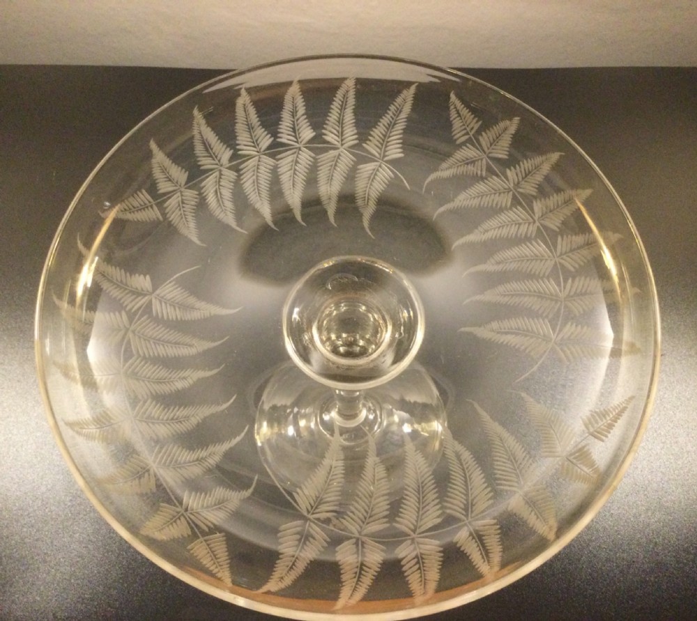 A clear Victorian lead crystal tazza featuring acid-etched fern leaves around the shallow circular dish, raised on a slender central stem and round footed base. View II