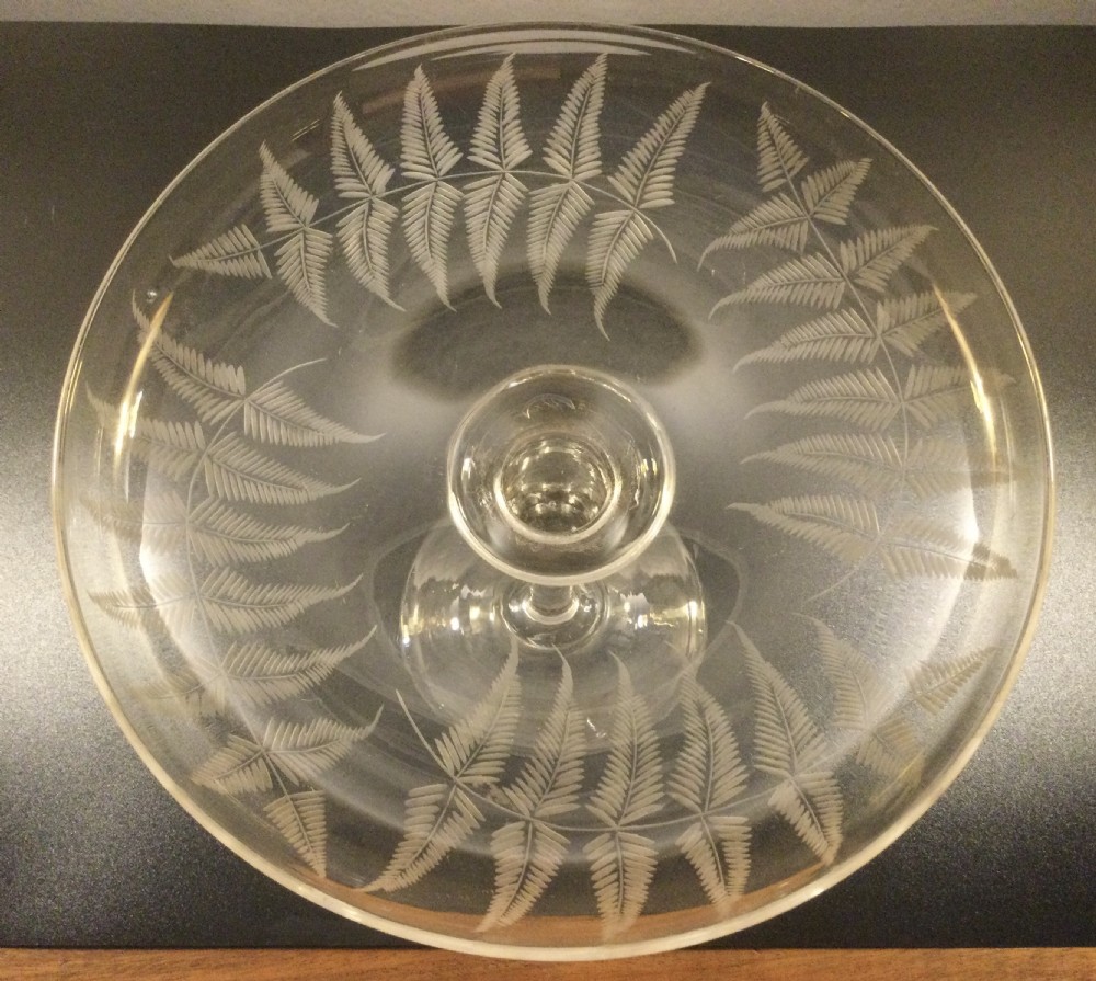 A clear Victorian lead crystal tazza featuring acid-etched fern leaves around the shallow circular dish, raised on a slender central stem and round footed base. View III