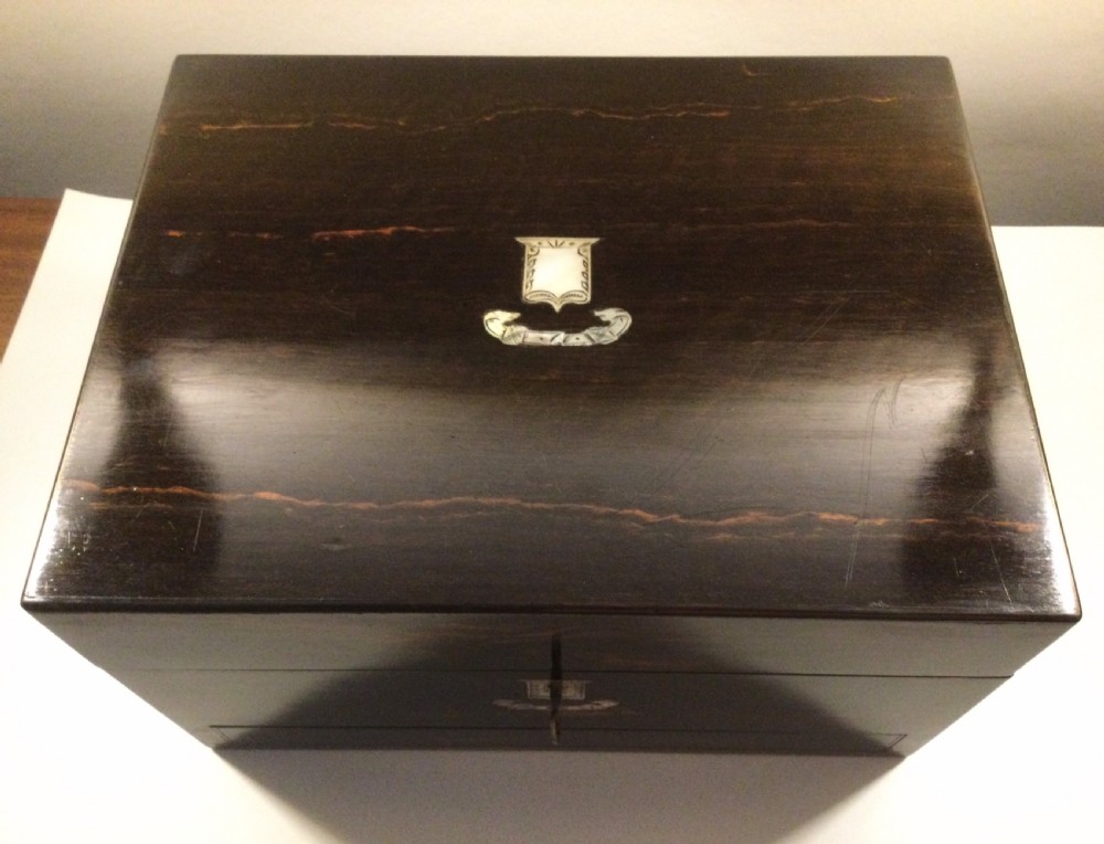 An early Victorian rectangular dark brown coromandel wood box featuring mother-of-pearl inlaid shield and crest motifs on the top lid and front panel. View III