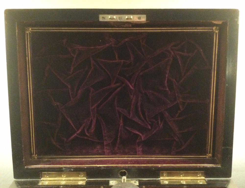 An early Victorian rectangular dark brown coromandel wood box featuring mother-of-pearl inlaid shield and crest motifs on the top lid and front panel. View IV