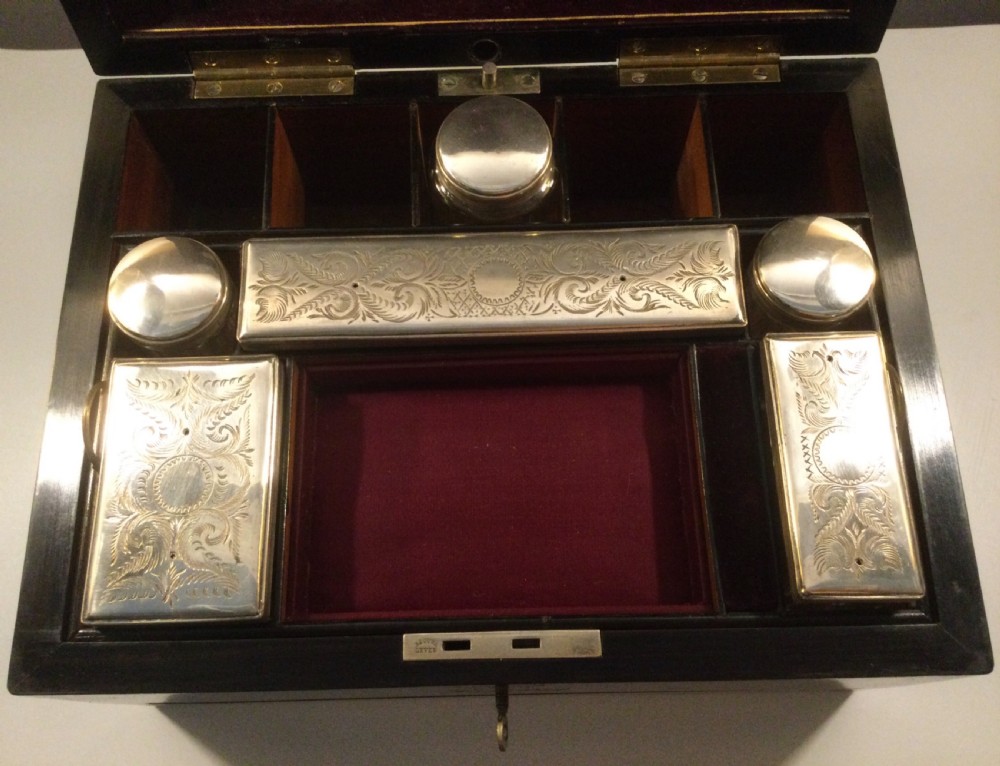 An early Victorian rectangular dark brown coromandel wood box featuring mother-of-pearl inlaid shield and crest motifs on the top lid and front panel. View V