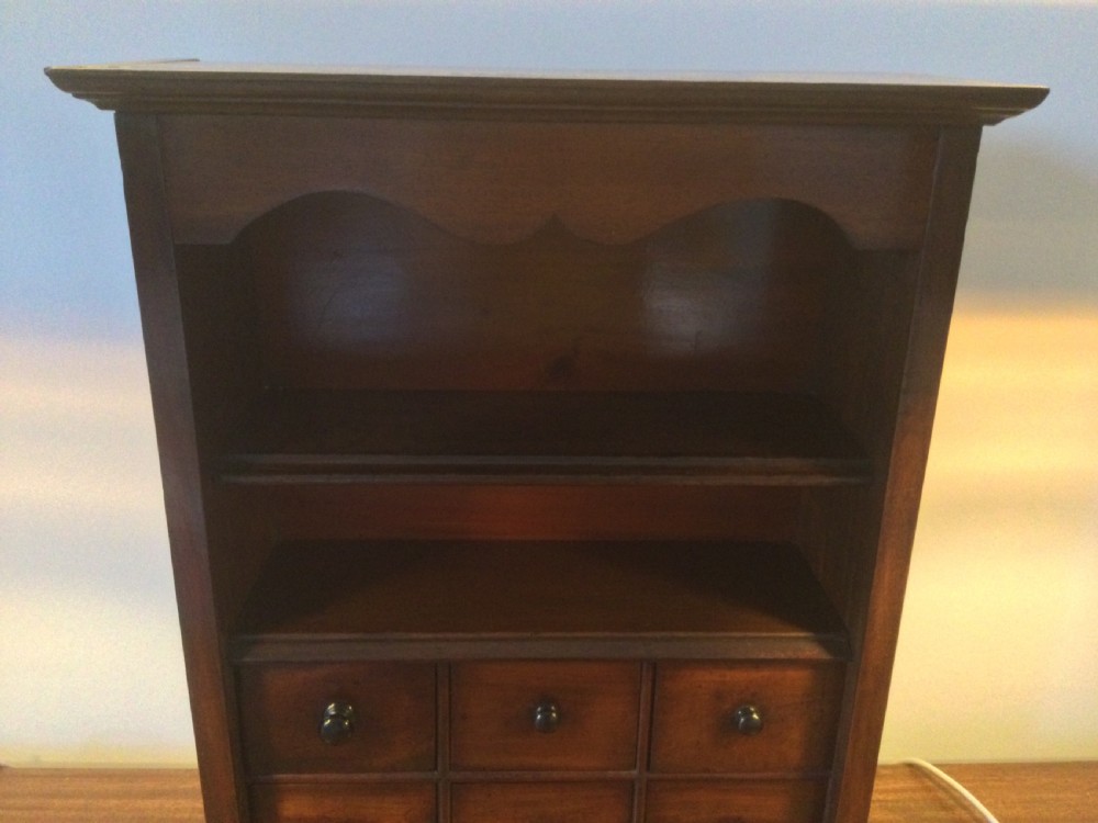 A mid-19th-century mahogany wall-hanging shelf unit featuring an open upper section above six small drawers with turned wooden knobs. View IV