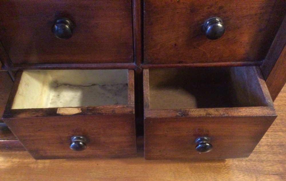 A mid-19th-century mahogany wall-hanging shelf unit featuring an open upper section above six small drawers with turned wooden knobs. View VII