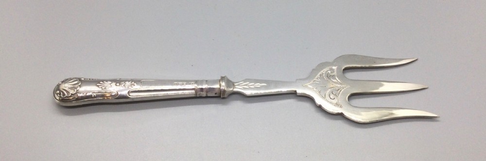 A three-piece Edwardian sterling silver serving set comprising a butter knife, pickle fork, and preserve spoon housed inside an open red velvet-lined presentation case. View V