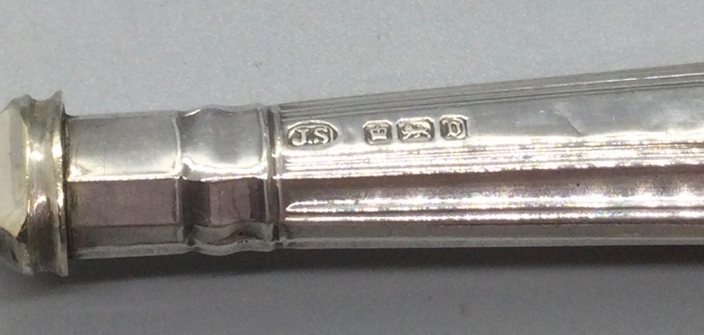 A three-piece Edwardian sterling silver serving set comprising a butter knife, pickle fork, and preserve spoon housed inside an open red velvet-lined presentation case. View VII