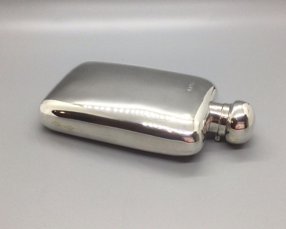 A curved rectangular sterling silver Edwardian spirit flask with a rounded domed cap and visible British hallmarks stamped near the shoulder. View III