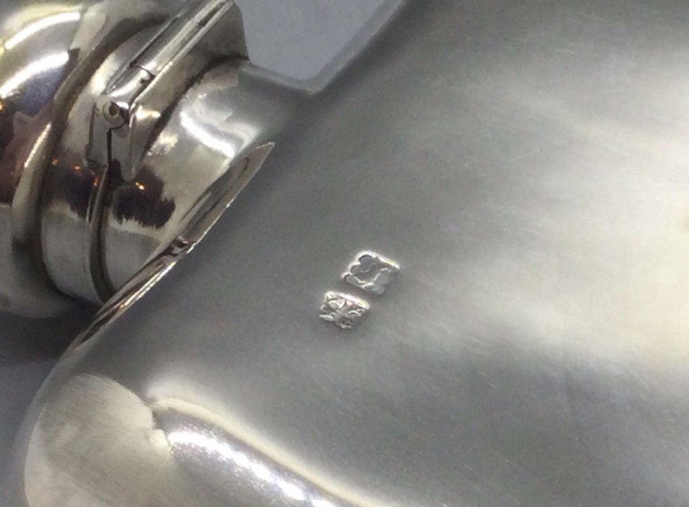 A curved rectangular sterling silver Edwardian spirit flask with a rounded domed cap and visible British hallmarks stamped near the shoulder. View VIII