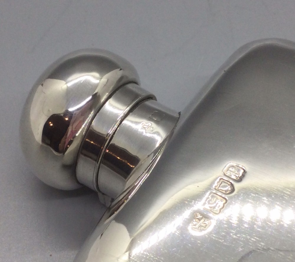 A curved rectangular sterling silver Edwardian spirit flask with a rounded domed cap and visible British hallmarks stamped near the shoulder. View IX