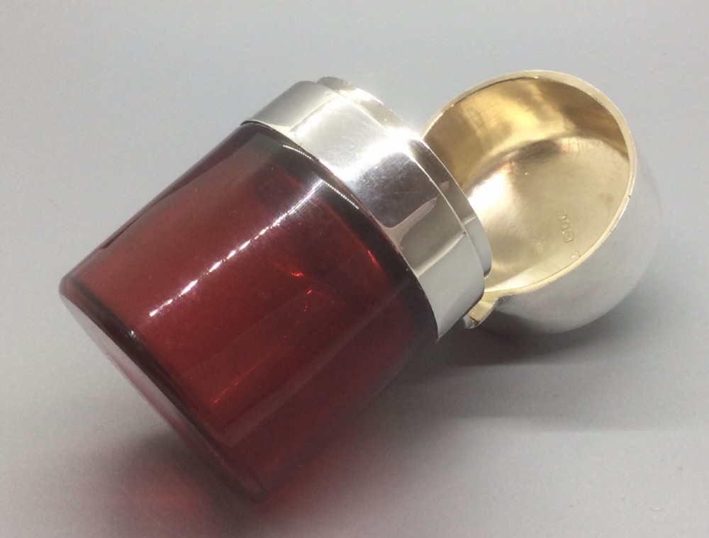 A Victorian cylindrical cranberry red glass scent bottle featuring a polished sterling silver domed lid. View X