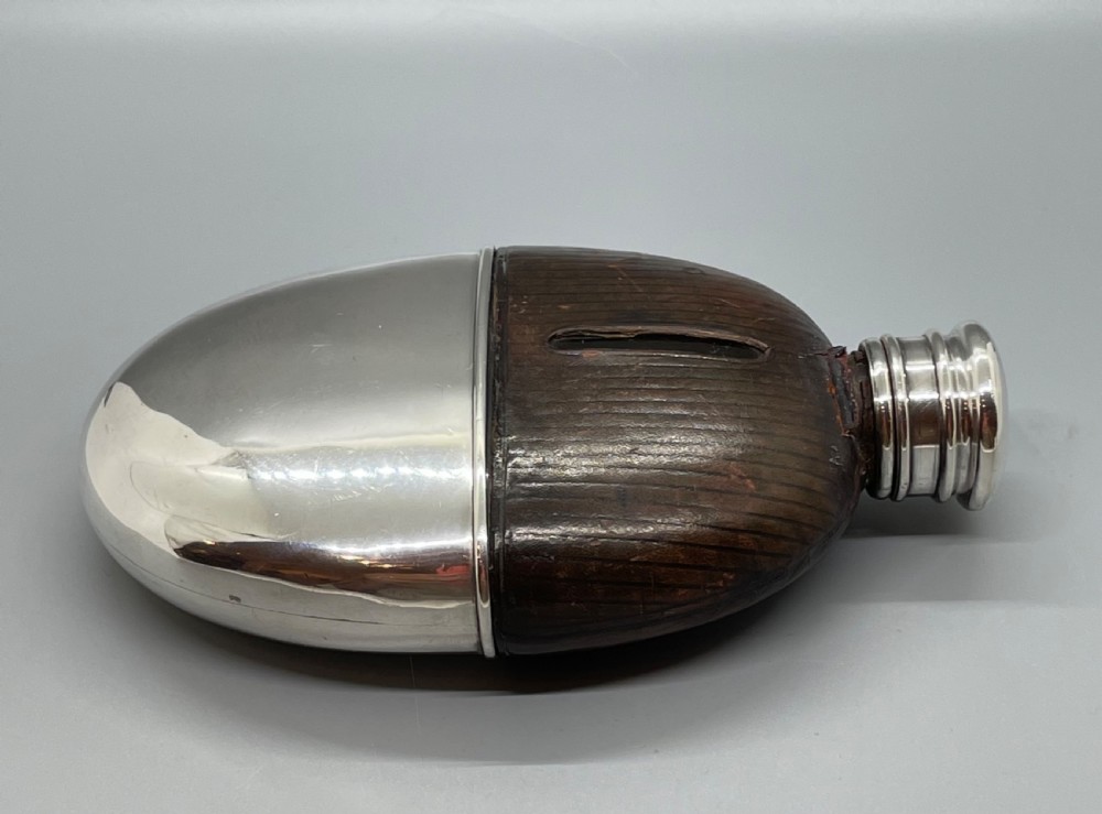 A Victorian spirit flask featuring a glass body encased in dark brown leather with a central sight window and a polished silver lower cup and cap. View XII