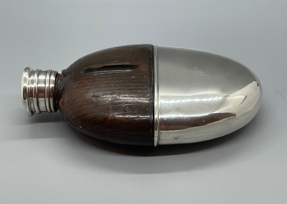 A Victorian spirit flask featuring a glass body encased in dark brown leather with a central sight window and a polished silver lower cup and cap. View XIII