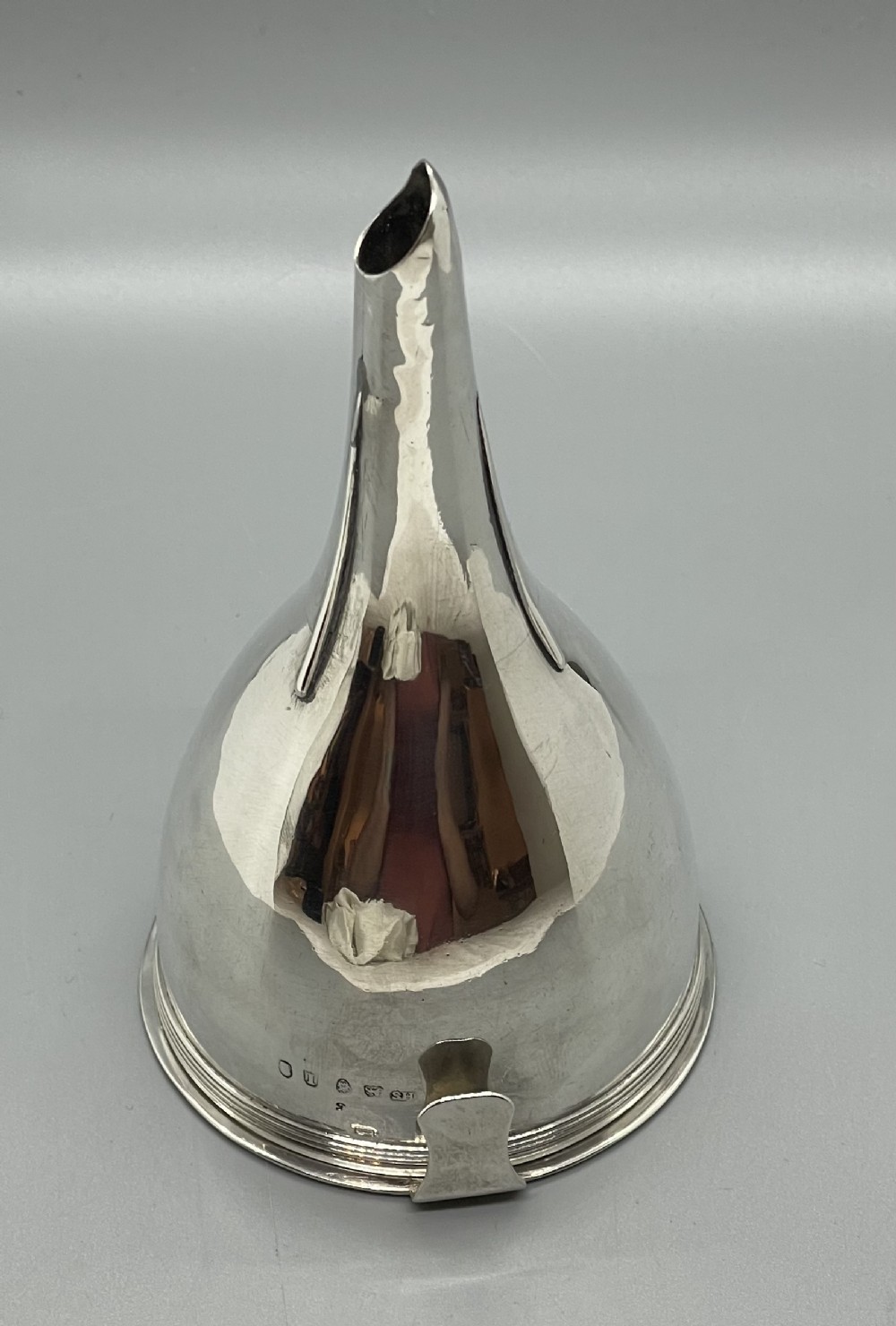 A sterling silver George III wine funnel featuring a reeded rim, side clip, curved spout, and London hallmarks.