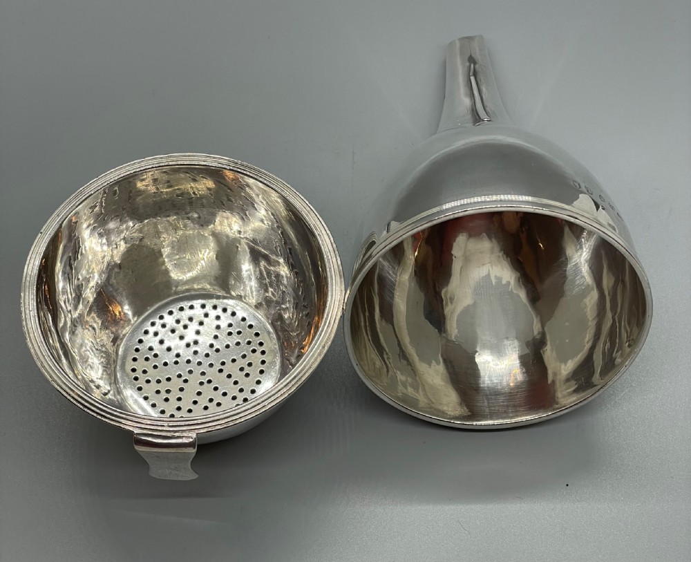 A sterling silver George III wine funnel featuring a reeded rim, side clip, curved spout, and London hallmarks. View V