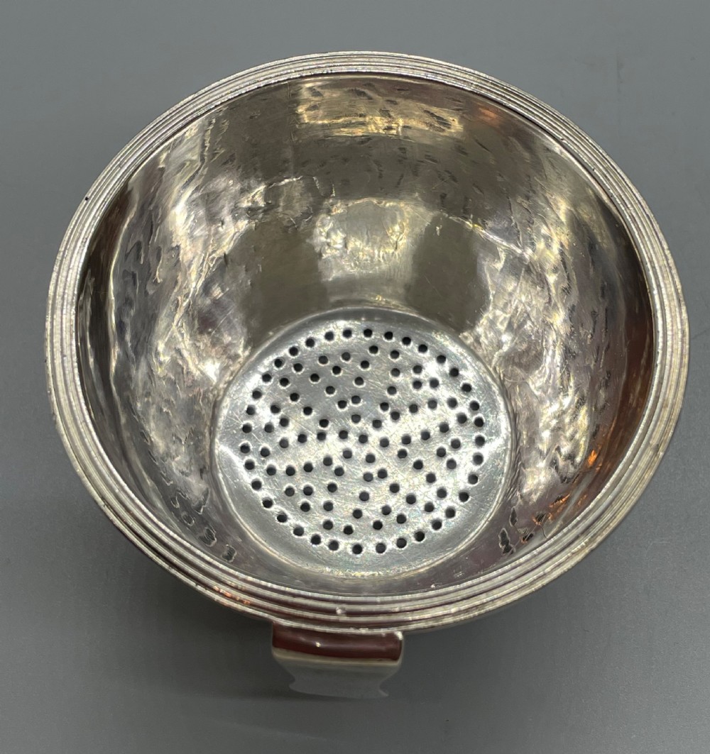 A sterling silver George III wine funnel featuring a reeded rim, side clip, curved spout, and London hallmarks. View VI