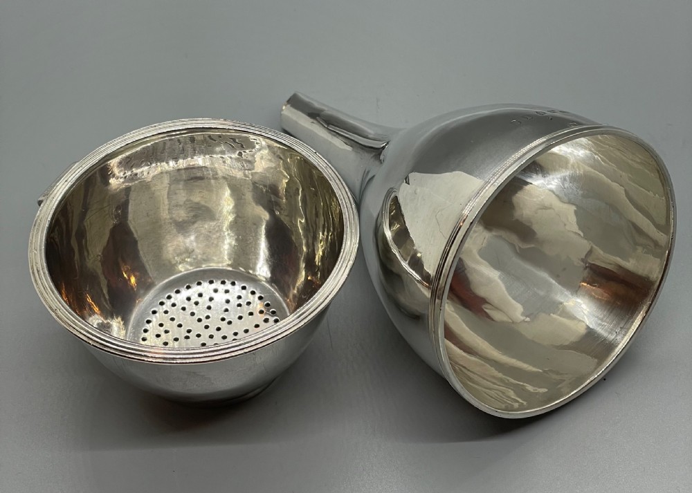 A sterling silver George III wine funnel featuring a reeded rim, side clip, curved spout, and London hallmarks. View X