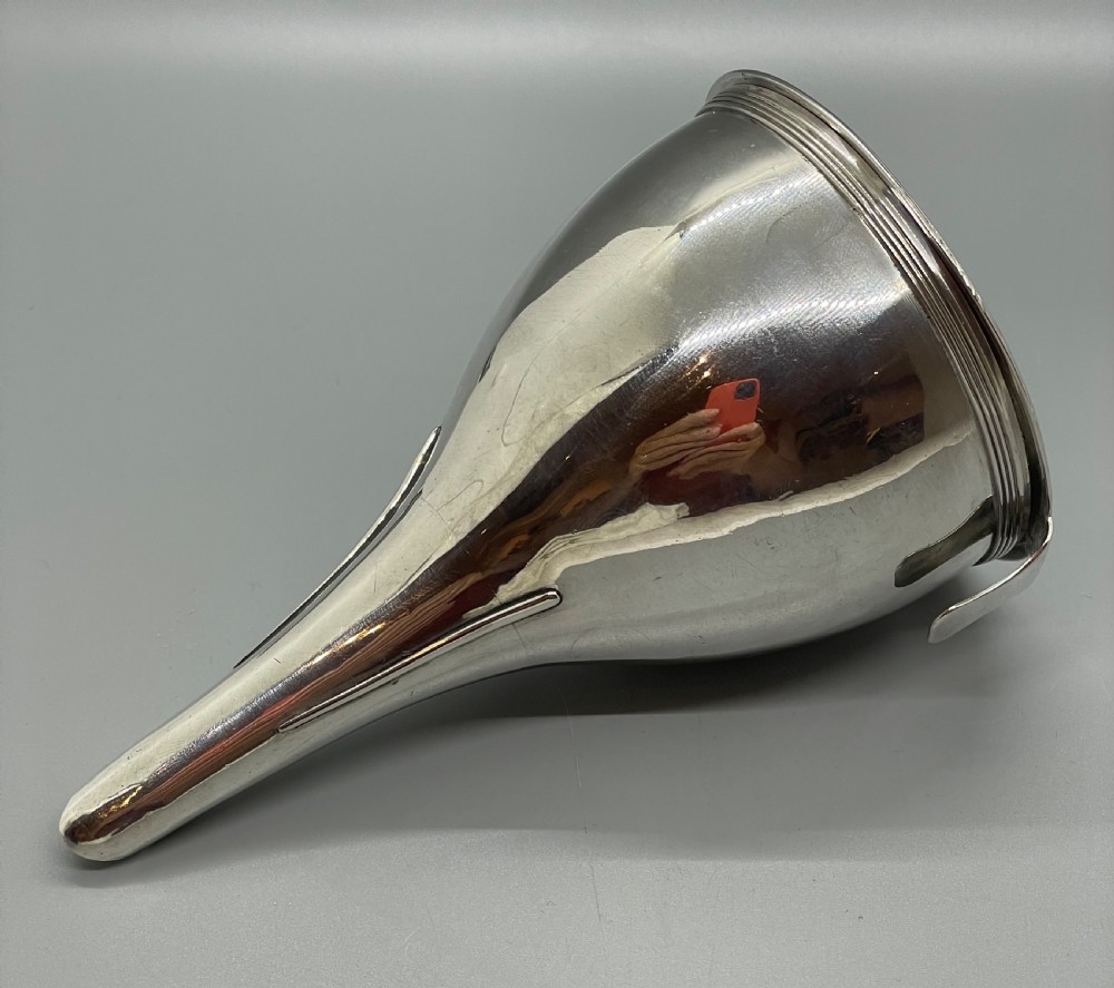 A sterling silver George III wine funnel featuring a reeded rim, side clip, curved spout, and London hallmarks. View XI