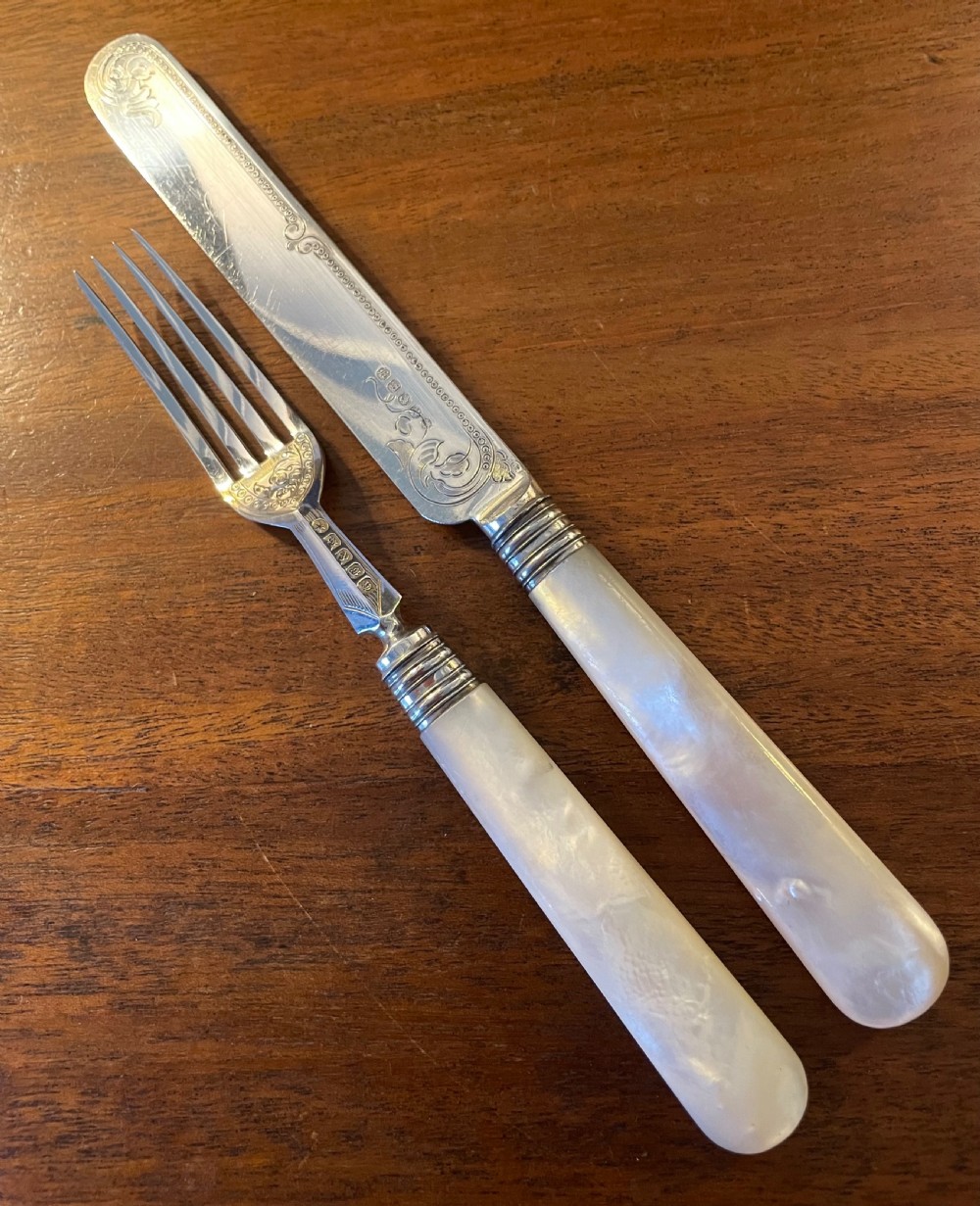 A Victorian silver-plated fruit cutlery set with mother-of-pearl handles displayed inside an open, blue velvet-lined wooden case. View VII