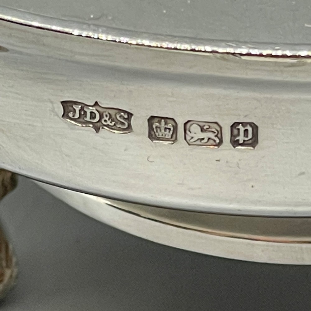 A pair of round Art Deco sterling silver bonbon dishes featuring twin scroll handles, lion paw feet, and visible Sheffield hallmarks. View III
