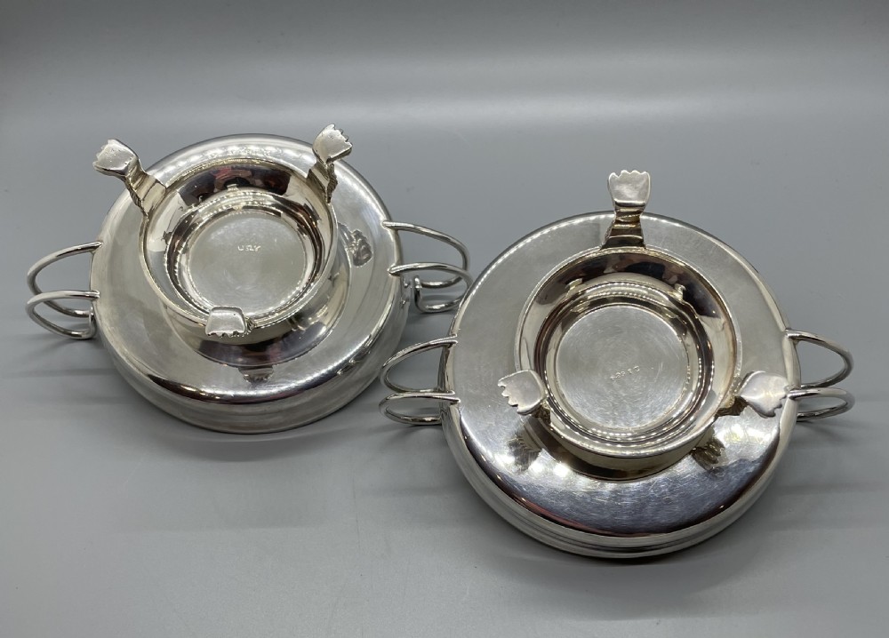 A pair of round Art Deco sterling silver bonbon dishes featuring twin scroll handles, lion paw feet, and visible Sheffield hallmarks. View VI
