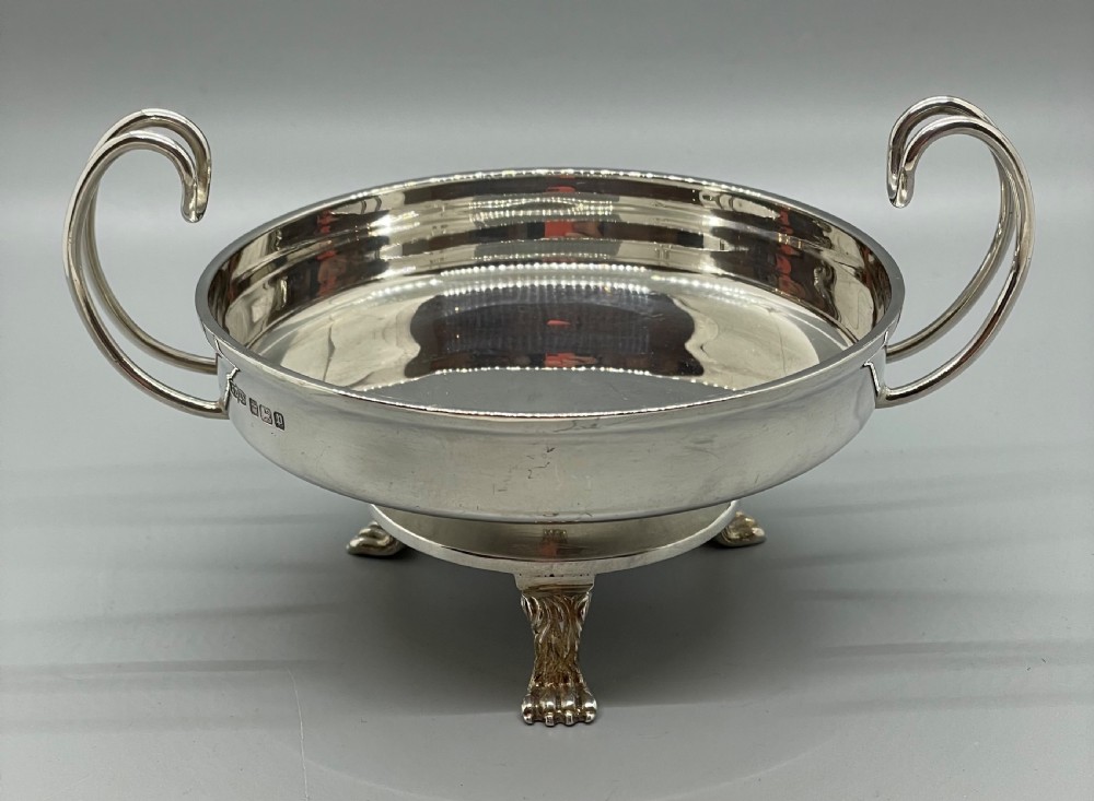 A pair of round Art Deco sterling silver bonbon dishes featuring twin scroll handles, lion paw feet, and visible Sheffield hallmarks. View VIII