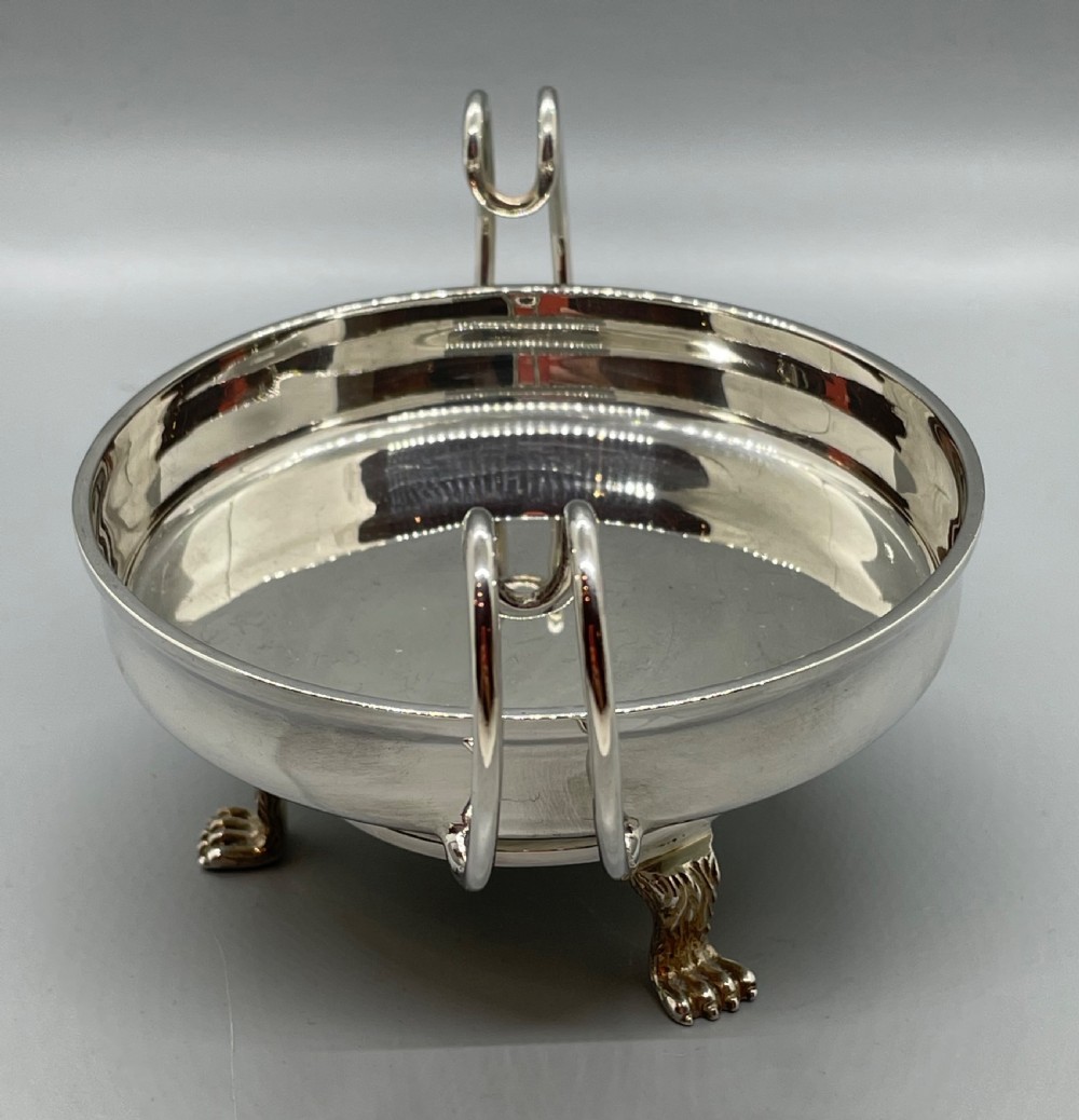 A pair of round Art Deco sterling silver bonbon dishes featuring twin scroll handles, lion paw feet, and visible Sheffield hallmarks. View X