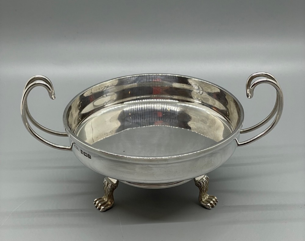 A pair of round Art Deco sterling silver bonbon dishes featuring twin scroll handles, lion paw feet, and visible Sheffield hallmarks. View XIII