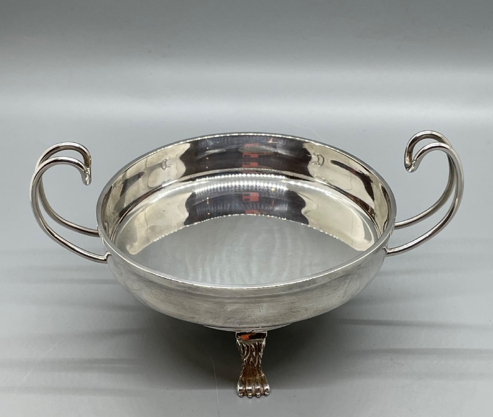 A pair of round Art Deco sterling silver bonbon dishes featuring twin scroll handles, lion paw feet, and visible Sheffield hallmarks. View XIV