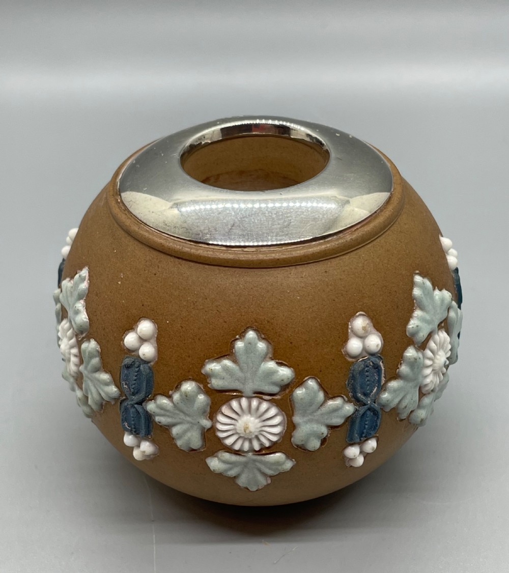 A spherical brown stoneware Victorian match striker featuring raised floral relief decoration and a polished sterling silver collar rim.