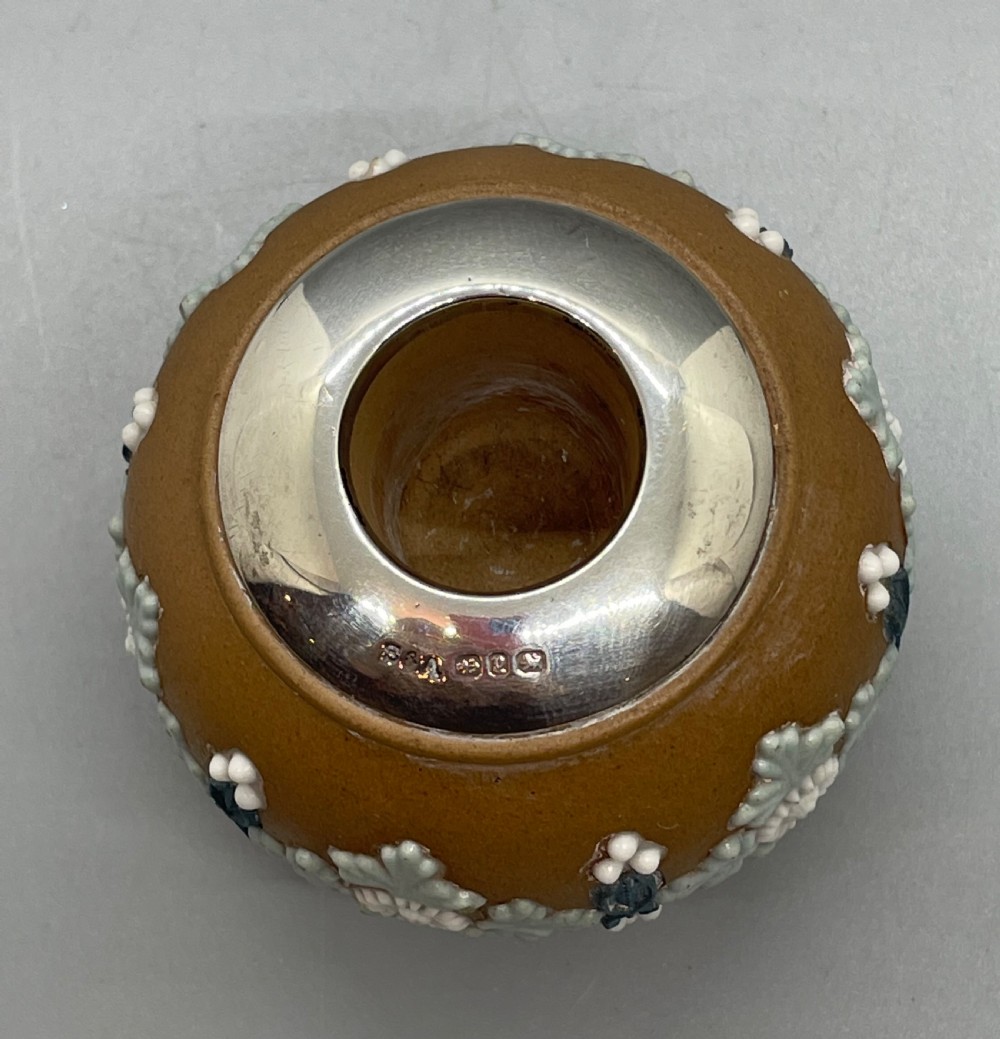 A spherical brown stoneware Victorian match striker featuring raised floral relief decoration and a polished sterling silver collar rim. View IV