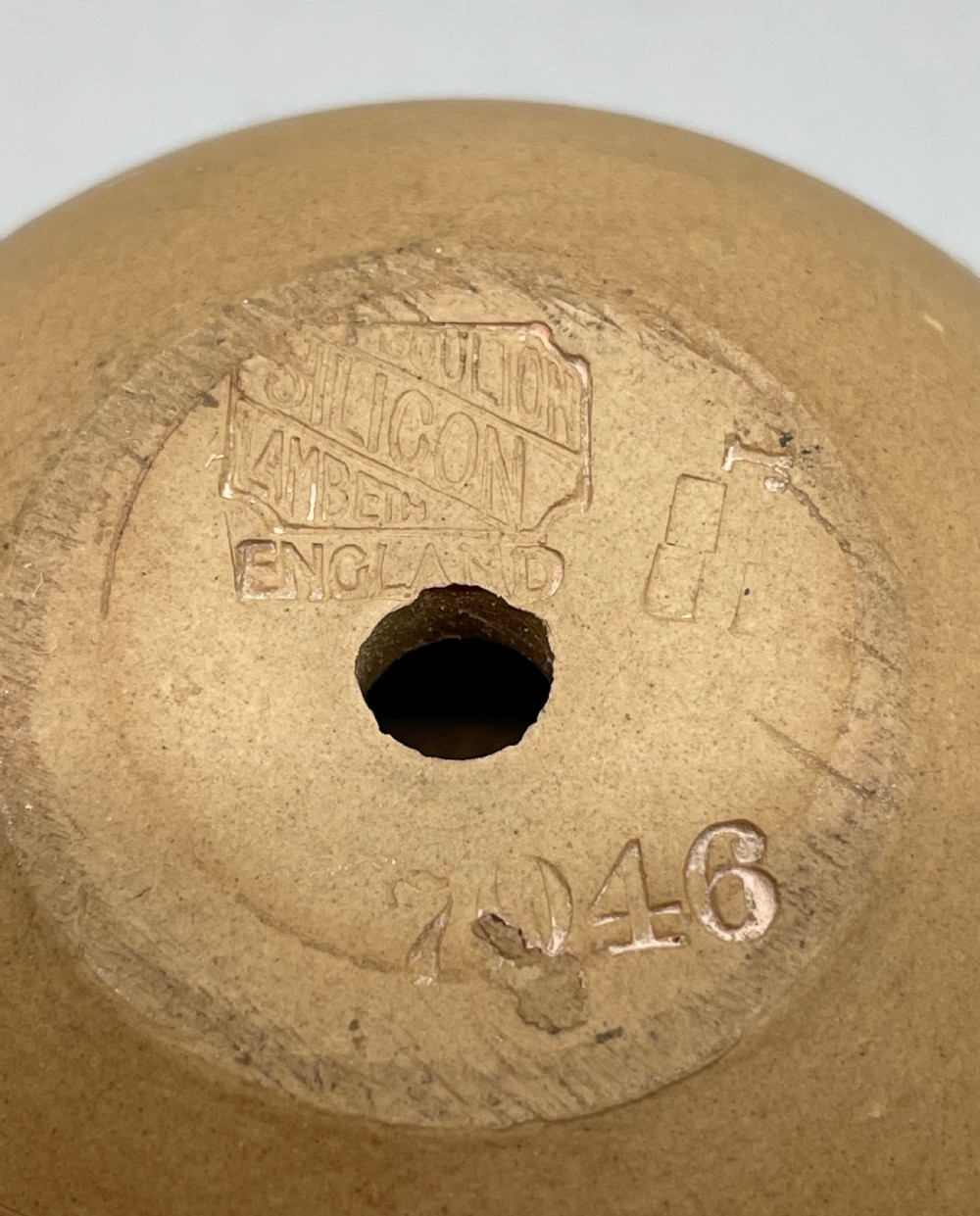 A spherical brown stoneware Victorian match striker featuring raised floral relief decoration and a polished sterling silver collar rim. View V