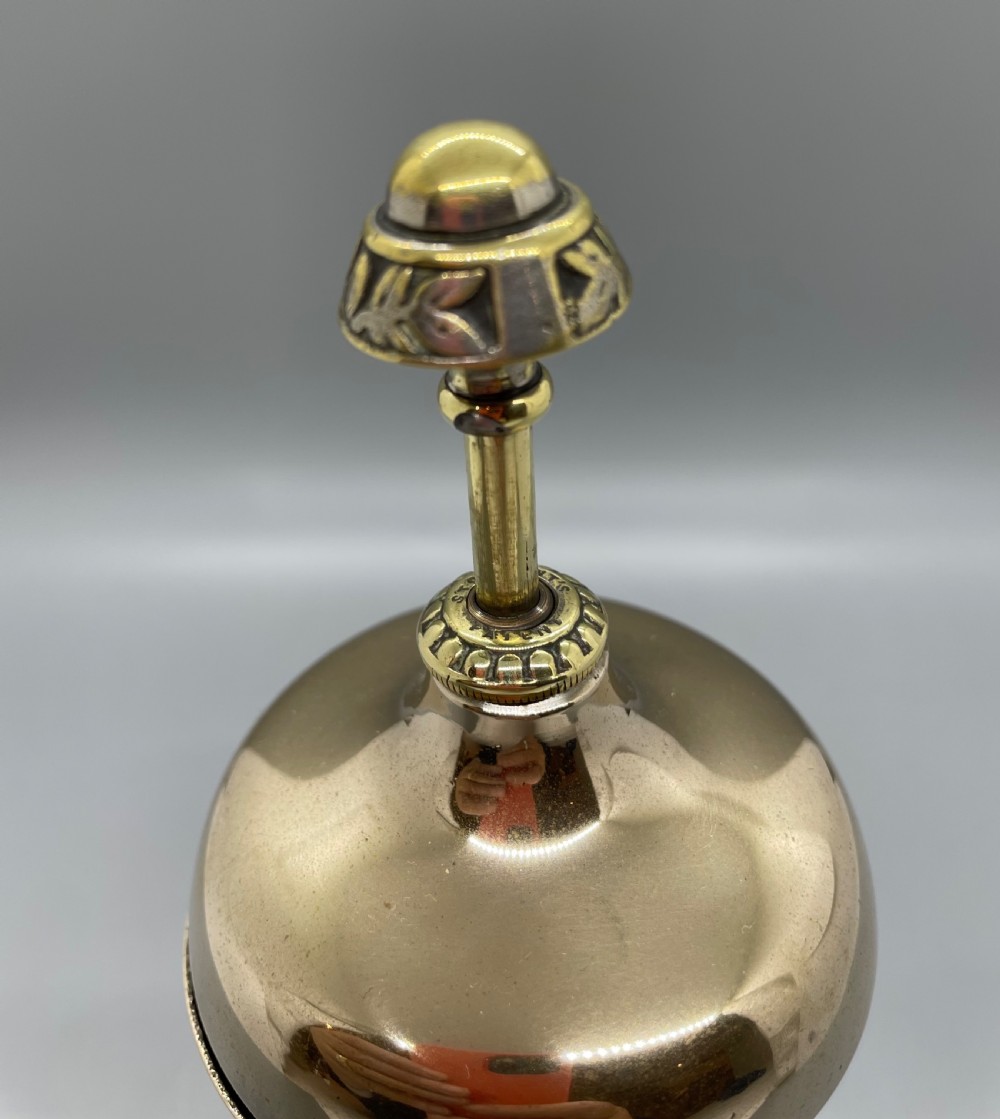 A late Victorian brass desk counter bell featuring an ornate pierced base, a dome top, and a decorative central push button. View V