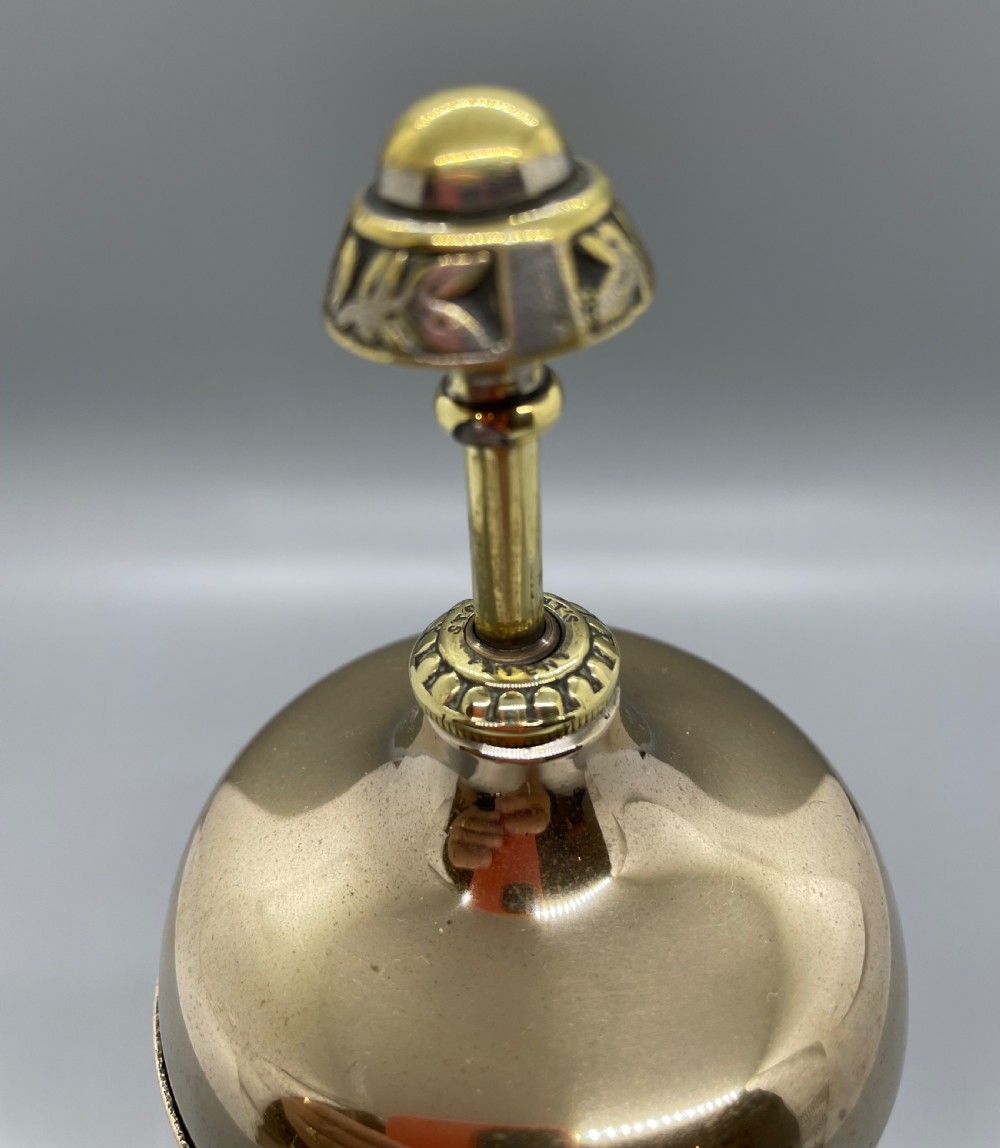 A late Victorian brass desk counter bell featuring an ornate pierced base, a dome top, and a decorative central push button. View VI
