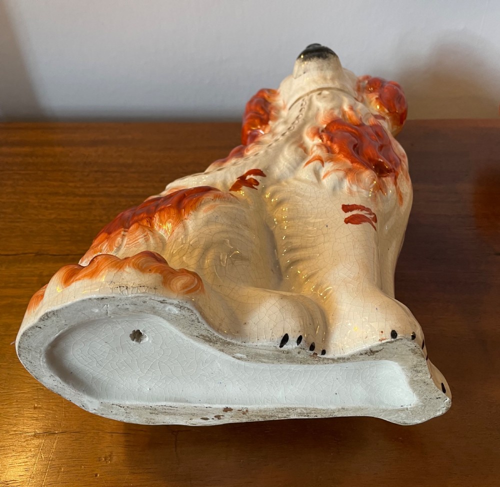 A pair of seated Victorian Staffordshire earthenware spaniel figurines featuring white glazed bodies with rust-red painted patches, black snouts, and gilded collars. View VII