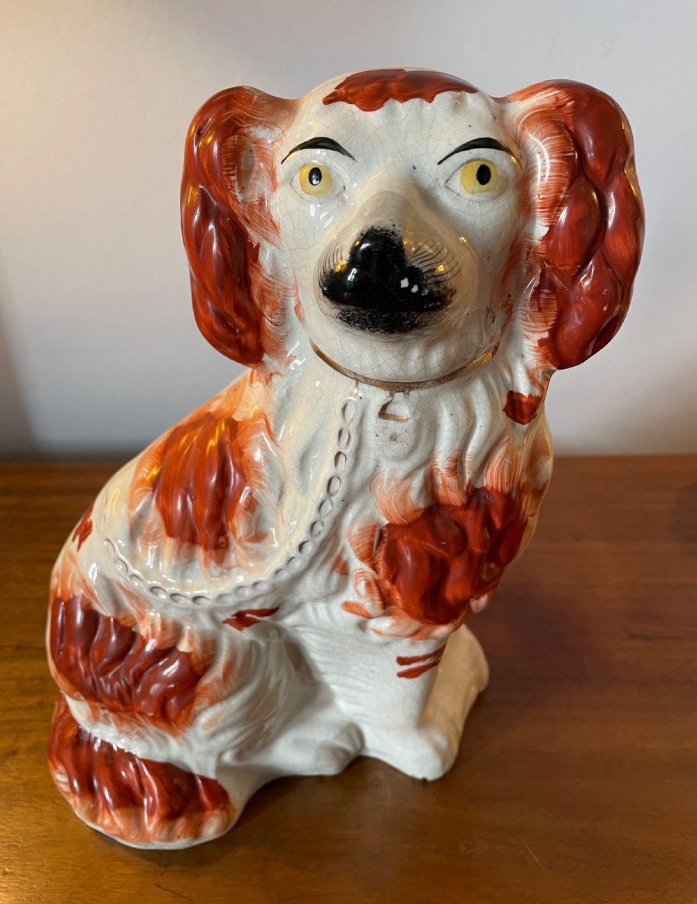A pair of seated Victorian Staffordshire earthenware spaniel figurines featuring white glazed bodies with rust-red painted patches, black snouts, and gilded collars. View VIII
